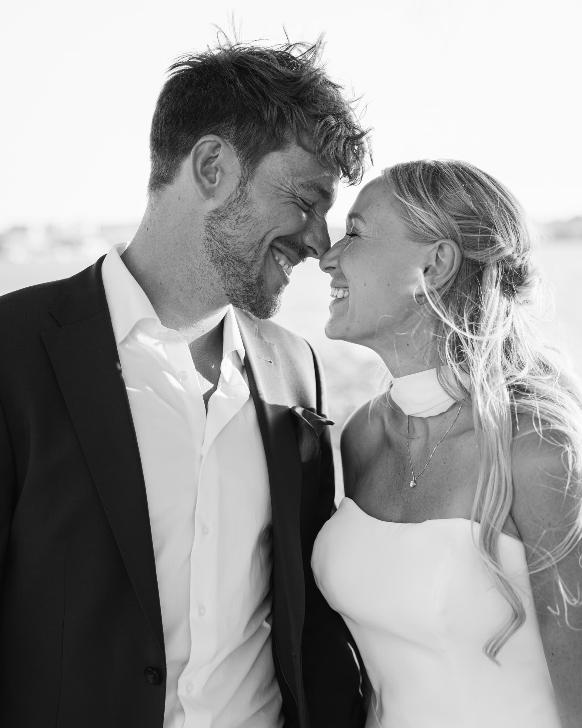 Black-and-white close portrait of a smiling couple in wedding attire.