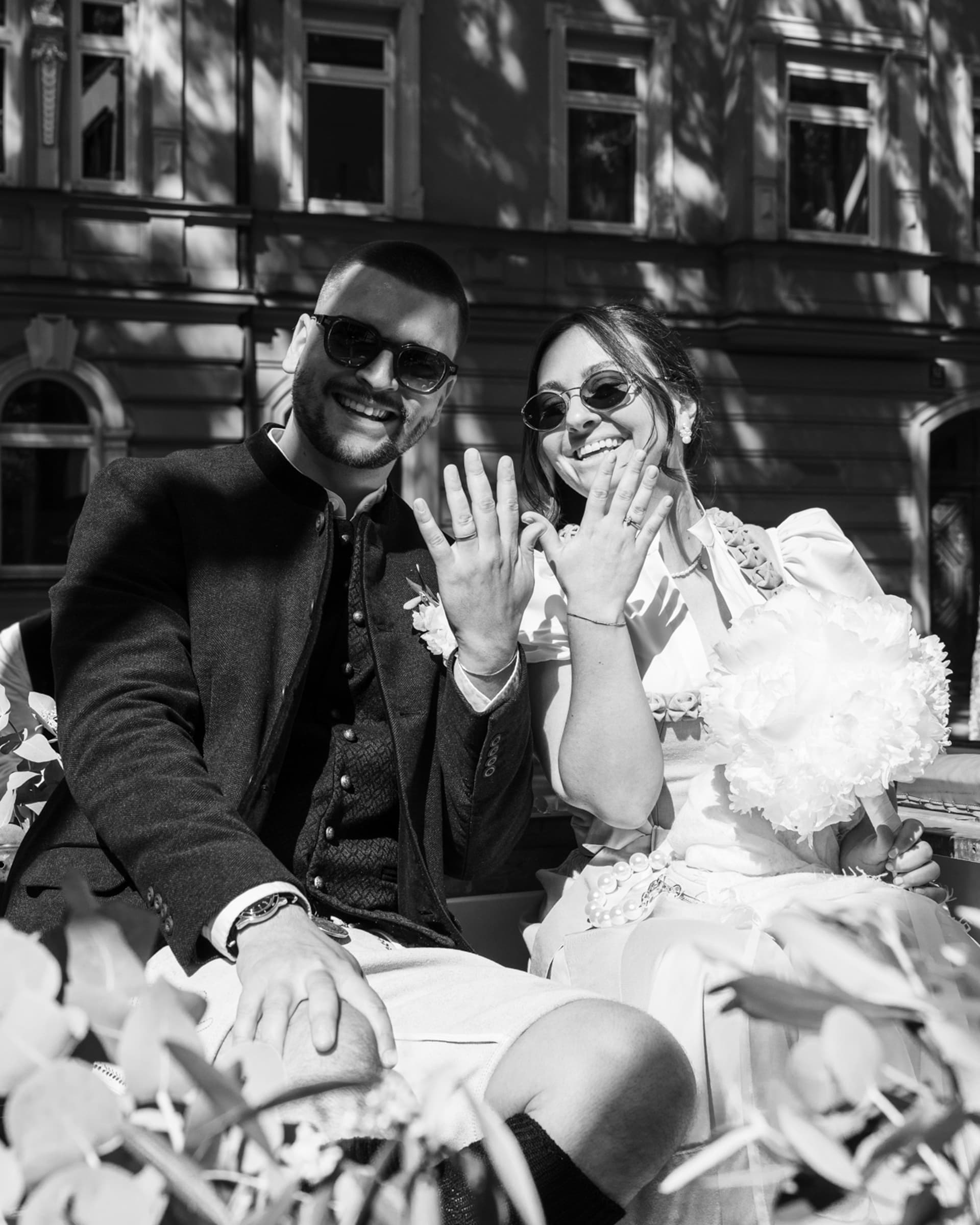 Black-and-white photo of a couple seated outdoors in front of a building.