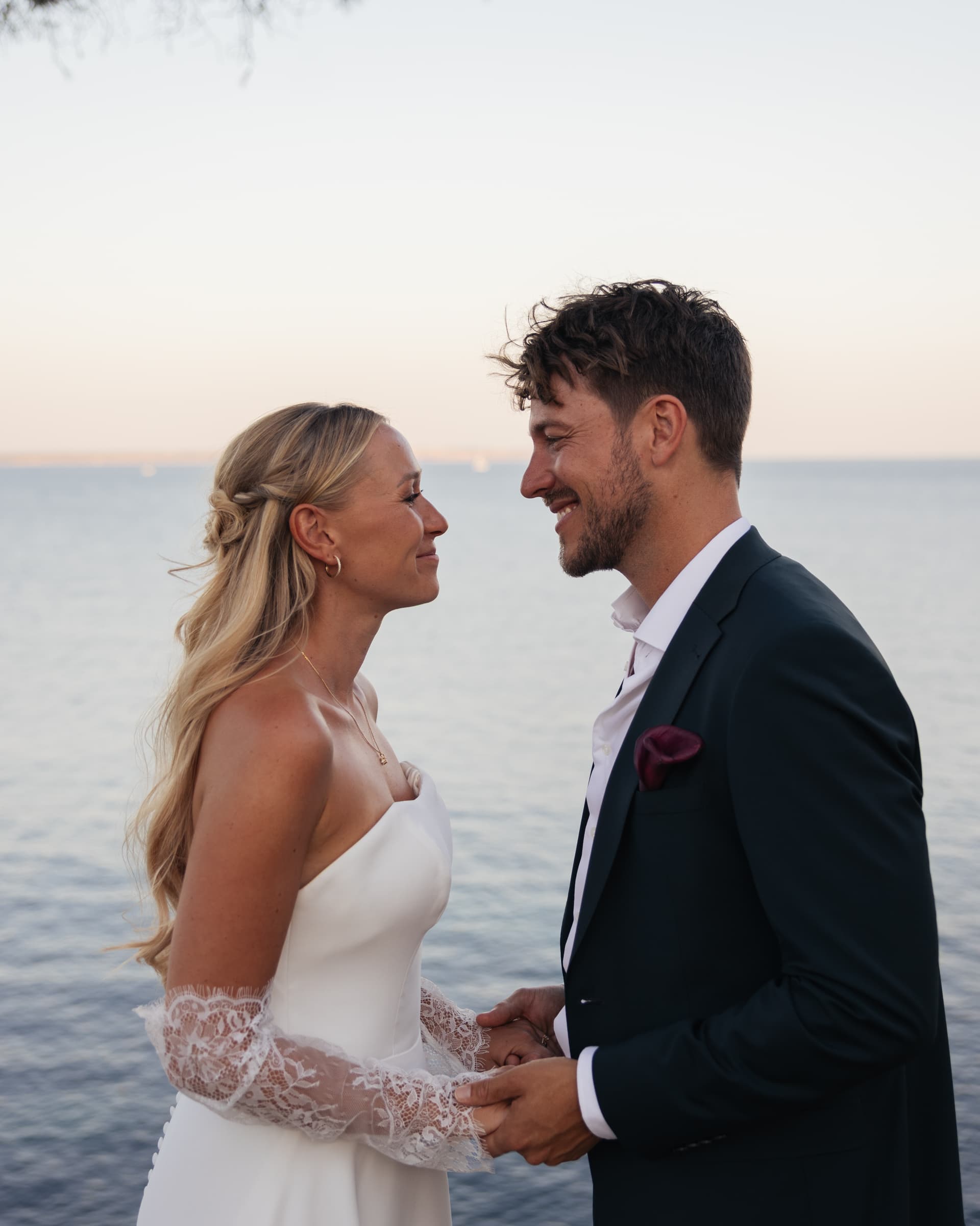 Close portrait of a couple in wedding attire facing each other at the coast.